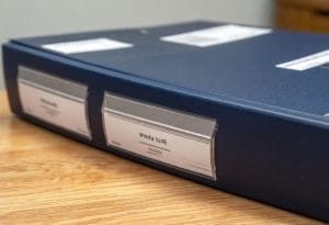 Fotografía sencilla de dos carpetas o expedientes diferentes sobre una mesa, una etiquetada como “FWU Life” y otra como “Fórum Filatélico”, mostrando contraste y comparación.